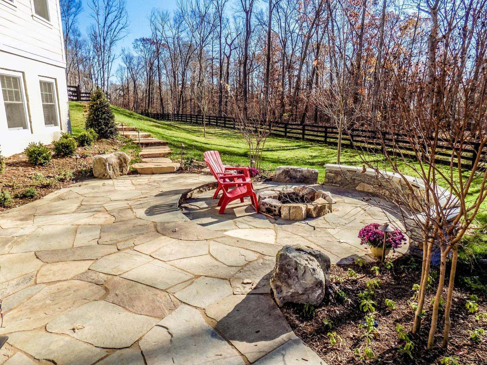 Flagstone patio with boulder fire pit and stone steps built by Outdoor Solutions on a fenced Northern Virginia acreage lot