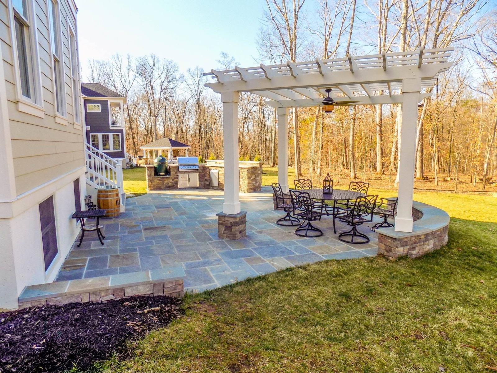 White pergola, bluestone patio, and stone outdoor kitchen with built-in grill — full outdoor living project by Outdoor Solutions in Northern Virginia